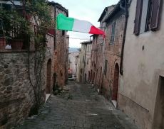 Una bandiera tricolore sventola su un vicolo di Montalcino